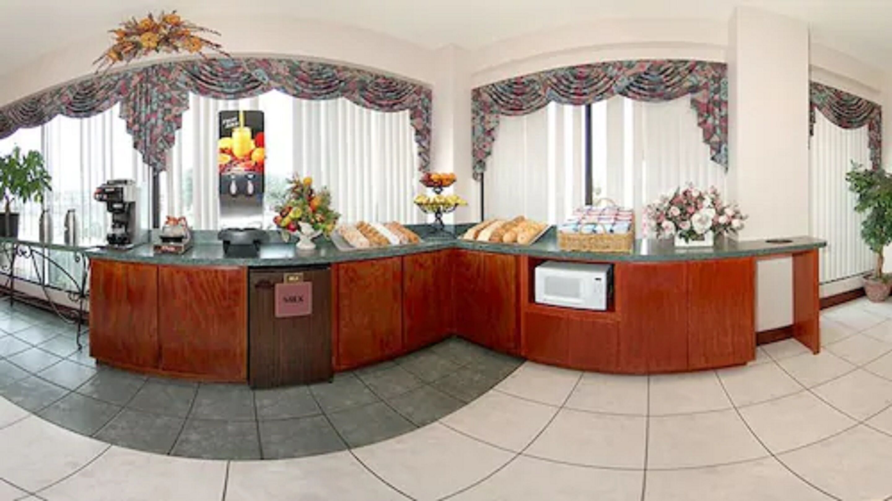 A curved reception desk with a built-in microwave, a coffee machine, and a fruit display.