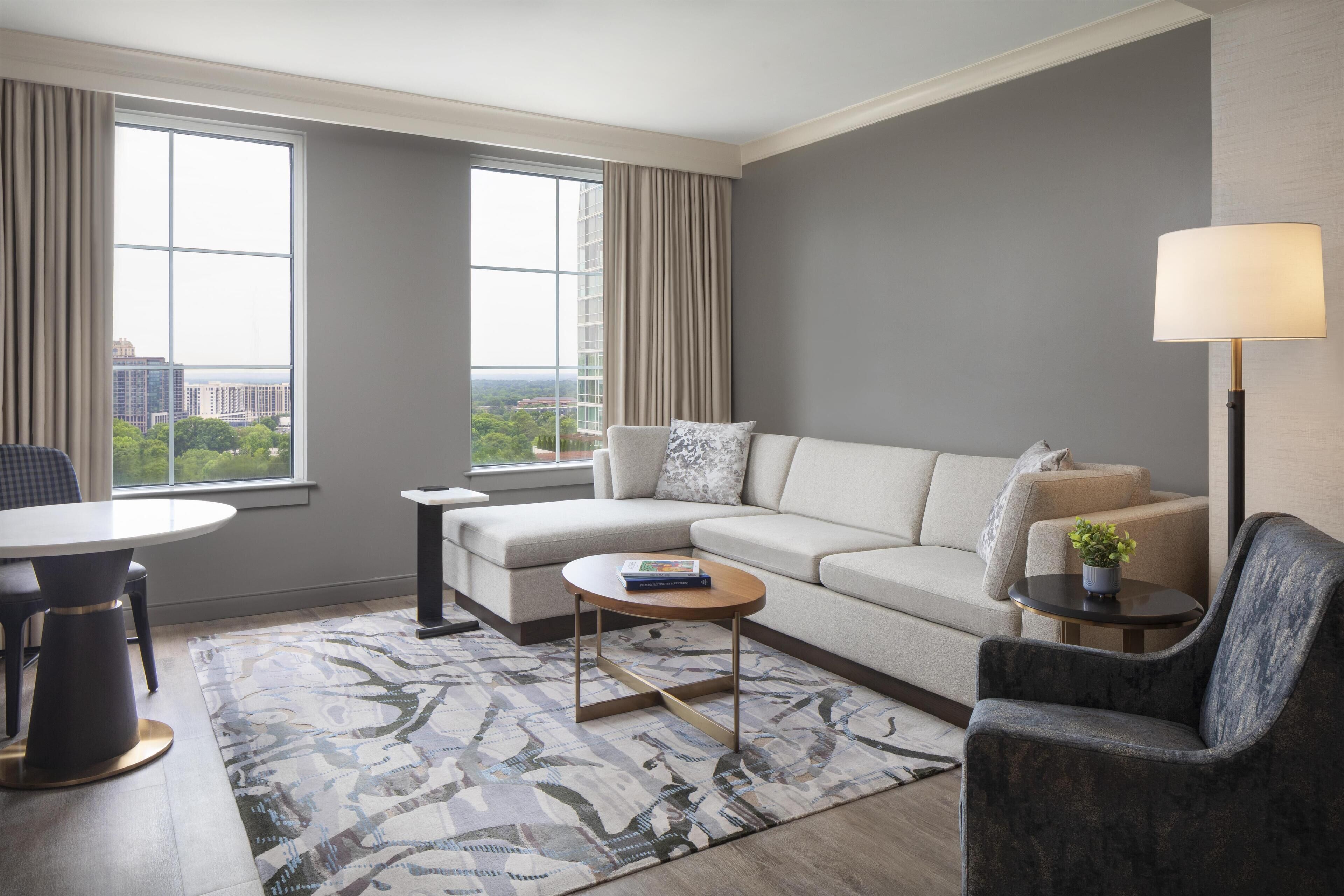 A modern living room with a sofa, armchair, coffee table, and a lamp.
