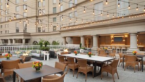 An outdoor patio area with wicker furniture, tables, and a fire feature. - Grand Hyatt Atlanta in Buckhead (Atlanta)
