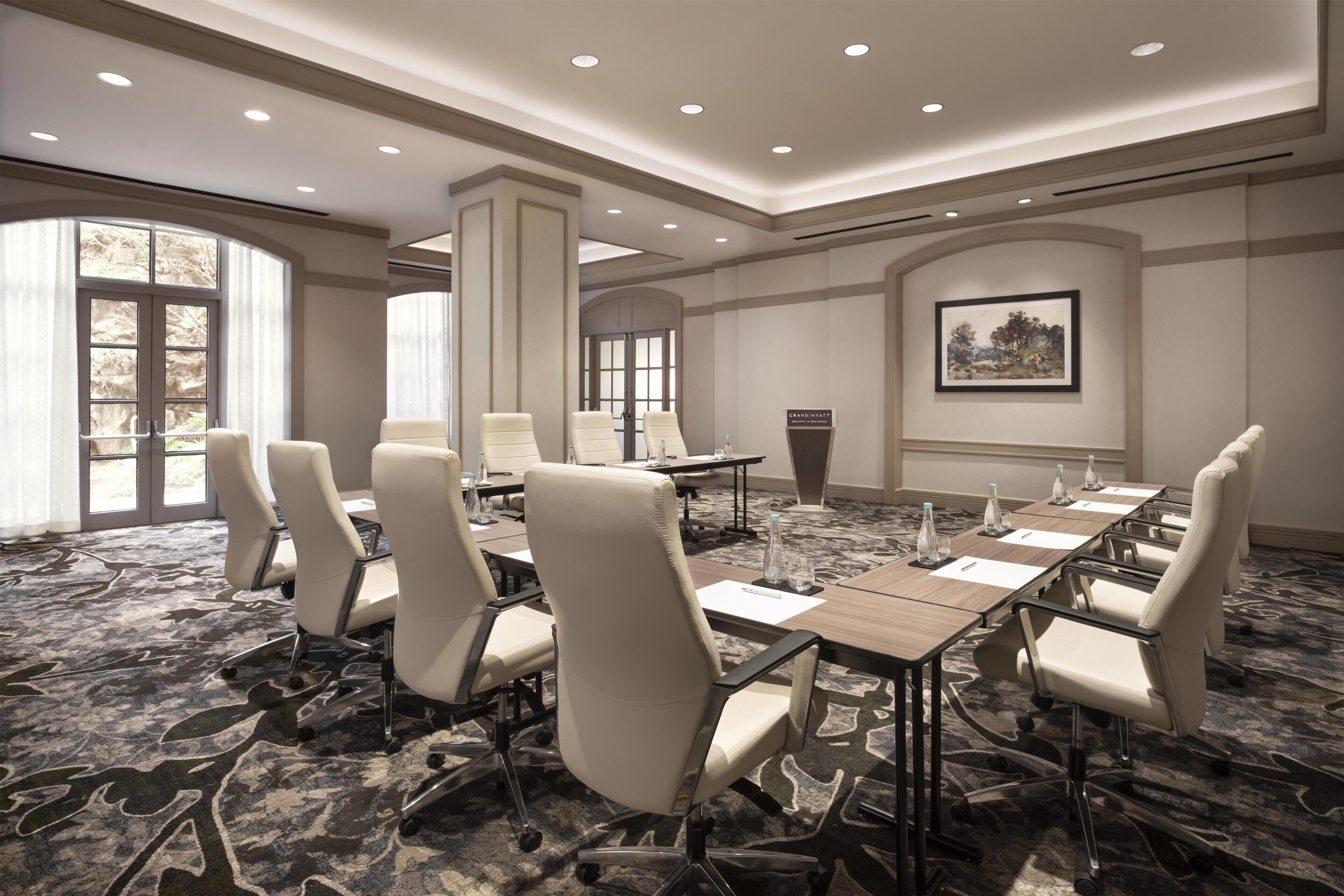 A conference room with a long table, several chairs, and a carpeted floor.