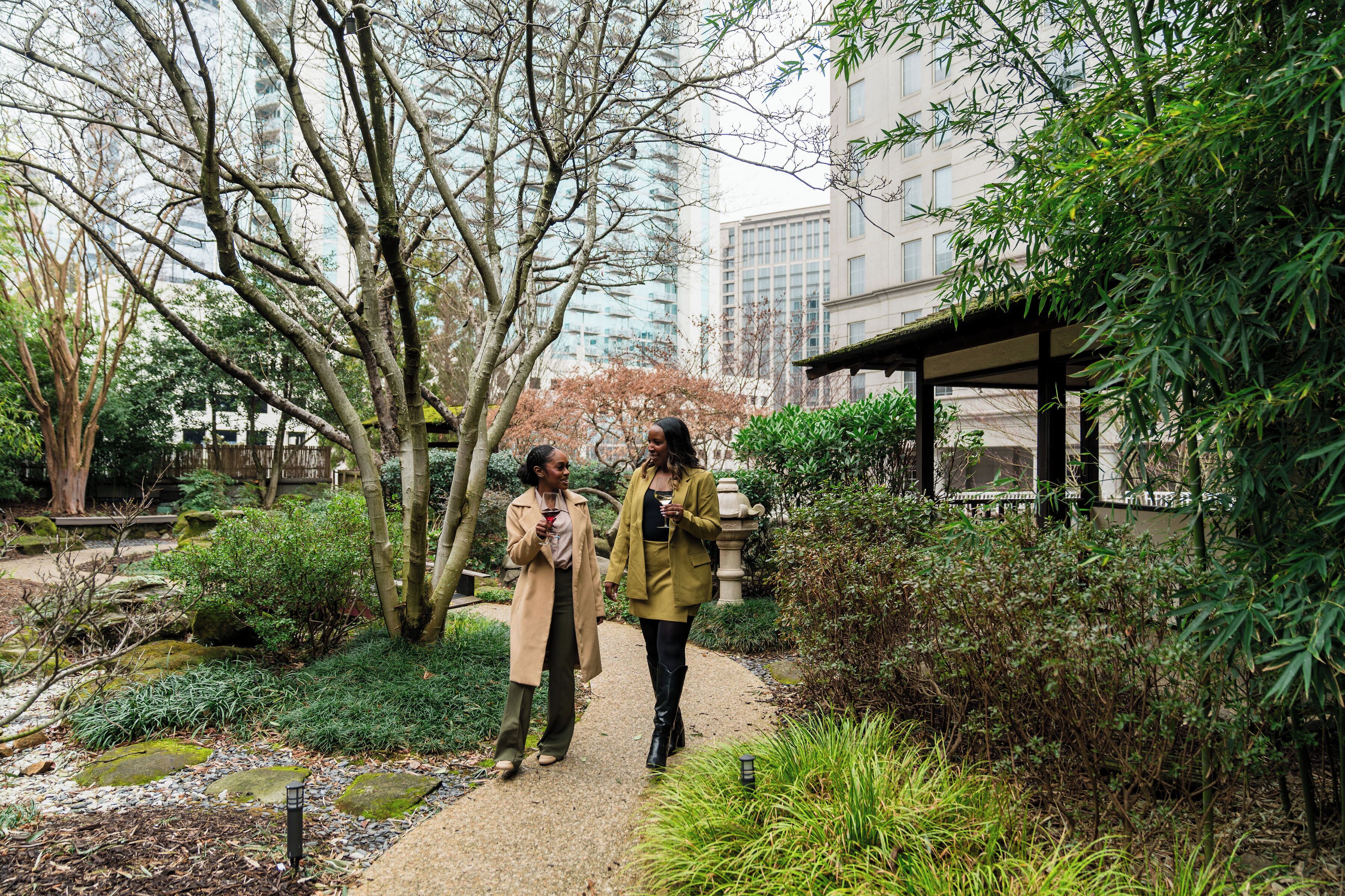A pathway in a garden with trees and a building in the background.