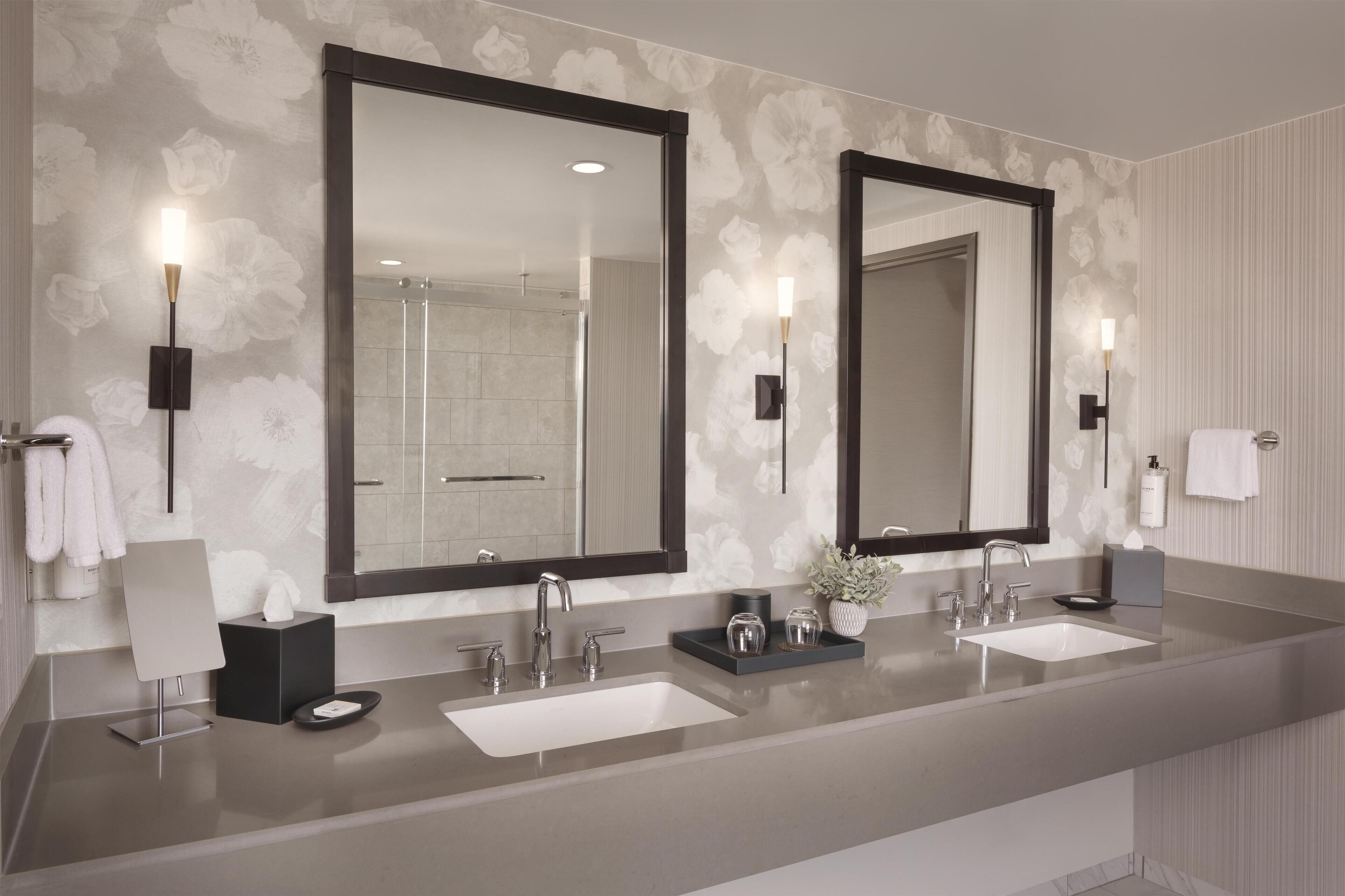 Une salle de bain moderne avec deux lavabos, de grands miroirs et un espace douche.