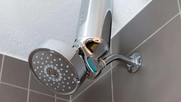 A modern showerhead with a curved design, mounted on a wall with a white textured surface.