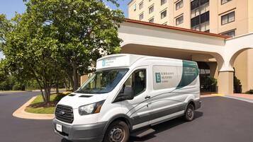 A white van with 'Embassy Suites by Hilton' branding parked in front of a building with a red roof.