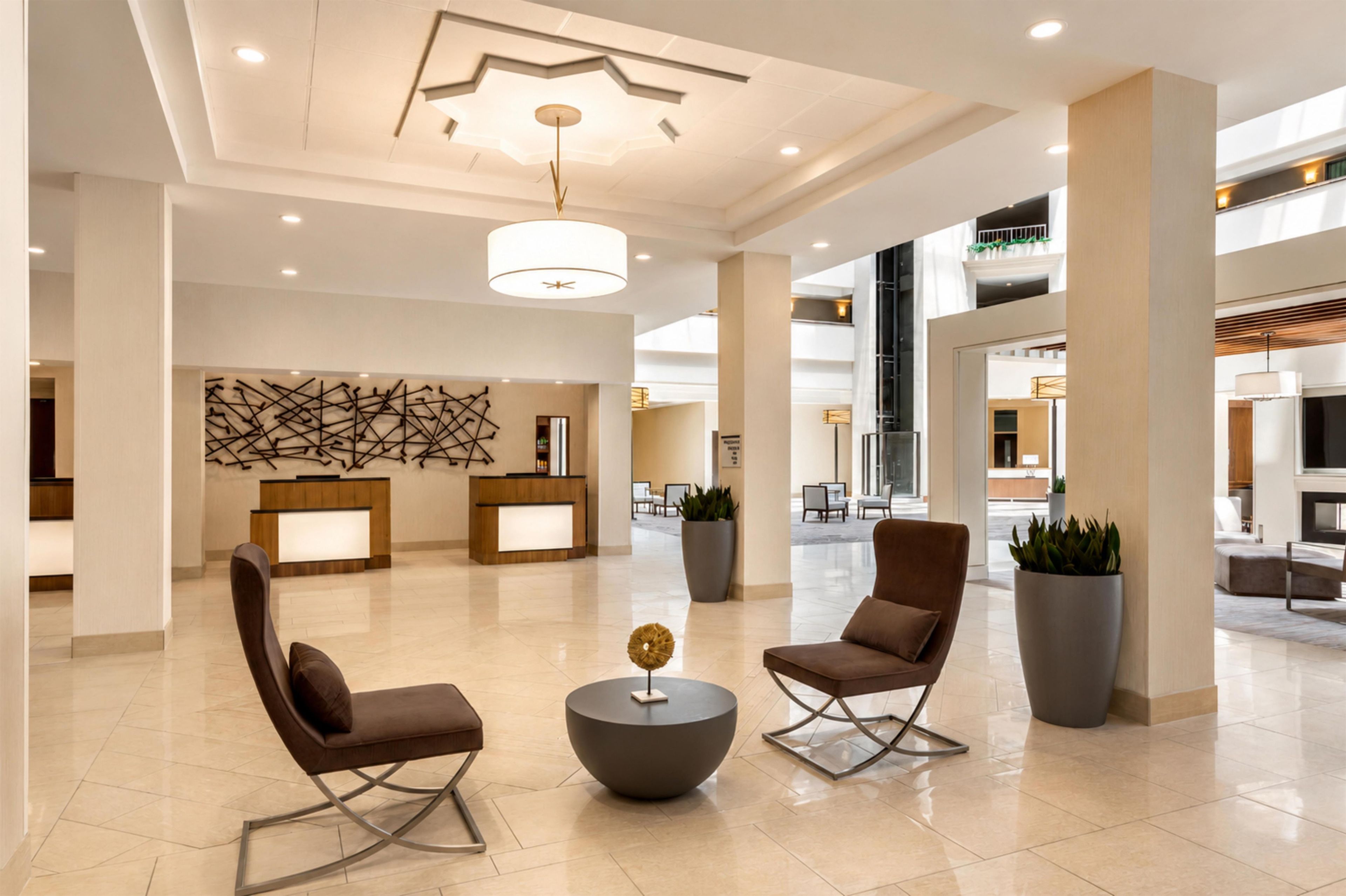 A spacious lobby with modern furniture, a reception desk, and a decorative ceiling design.