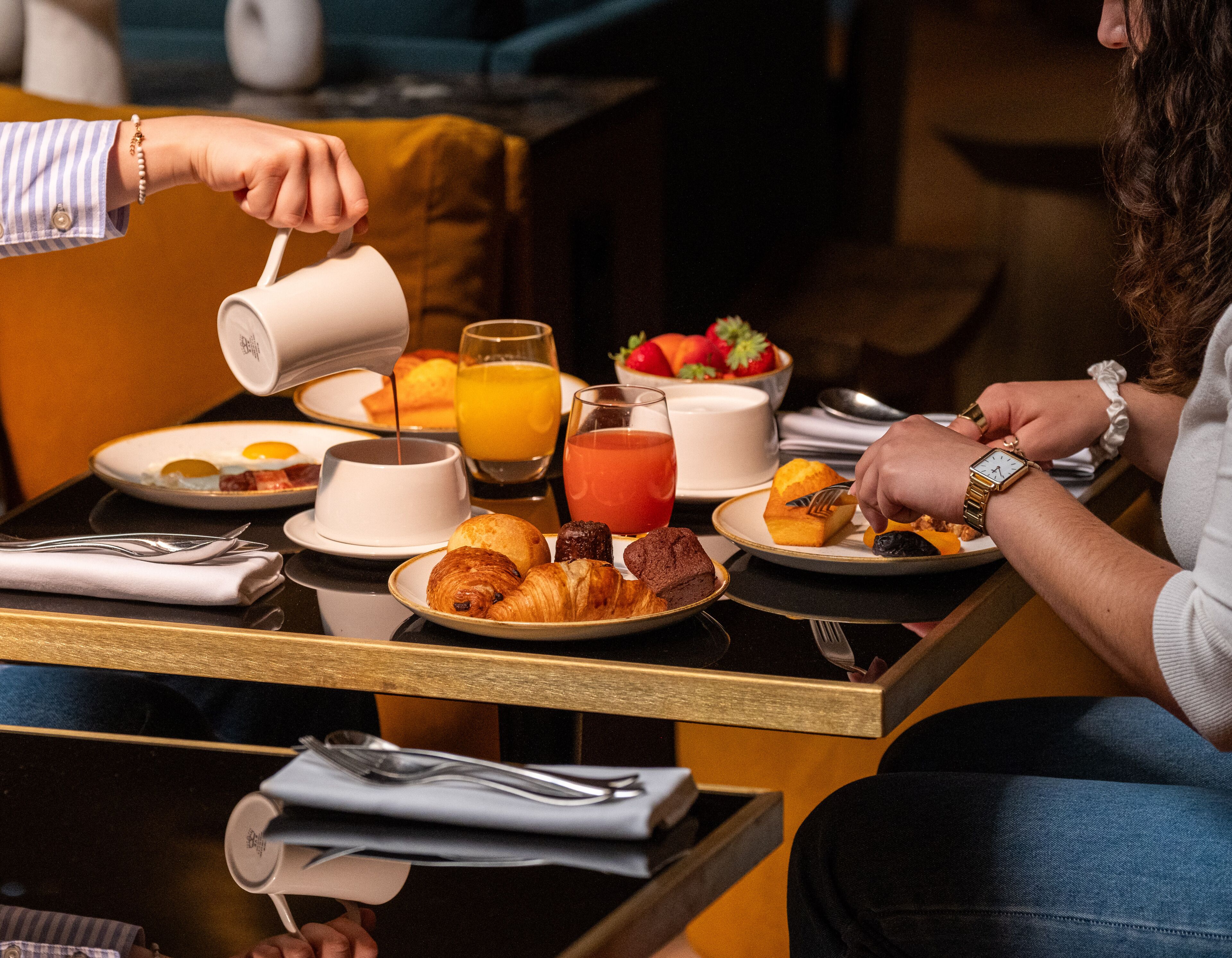 A breakfast setting with various food items and drinks on a table.