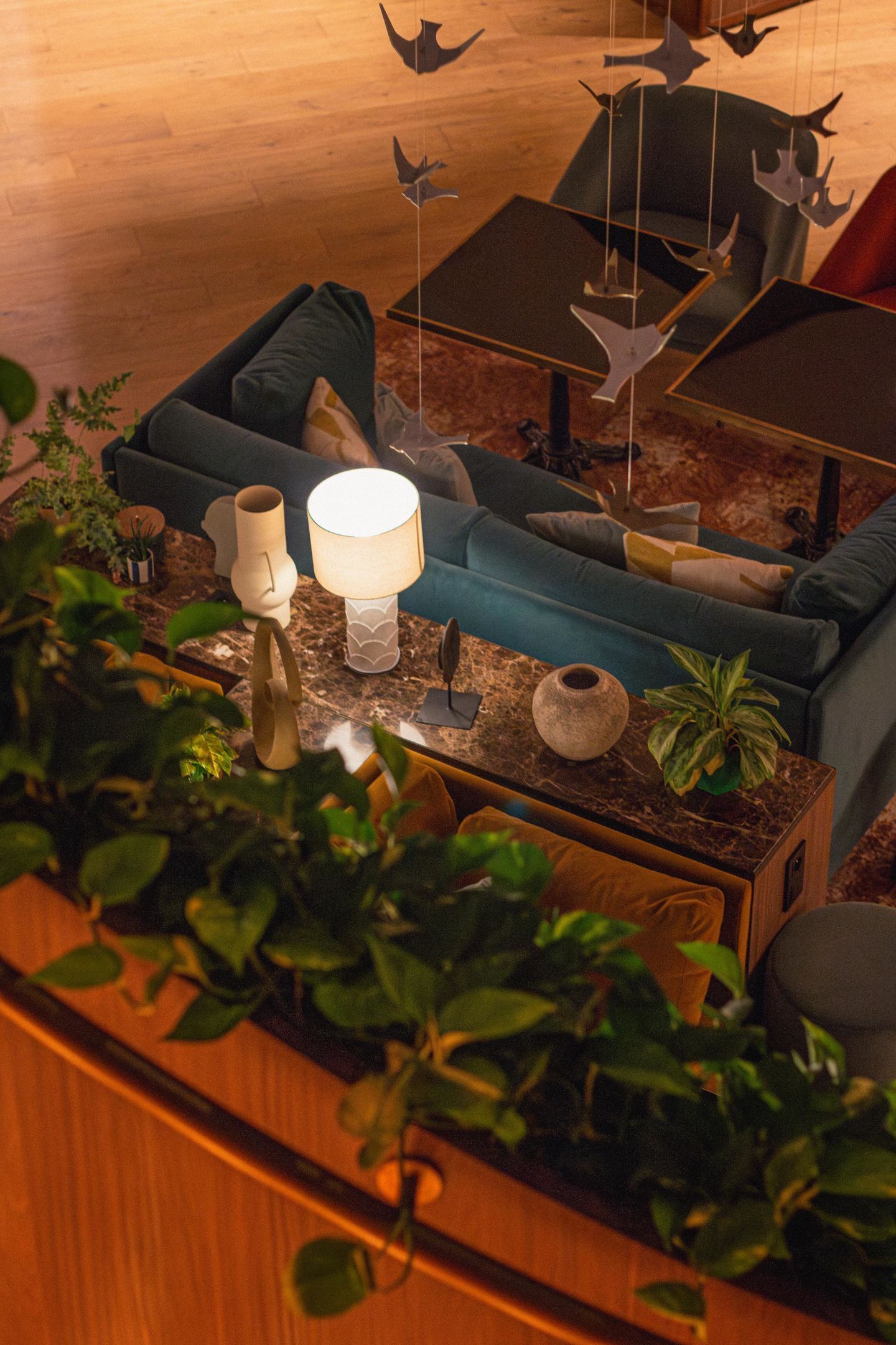 Una sala de estar acogedora con un sofá azul, una mesita de centro y elementos decorativos como una lámpara y un adorno colgante.