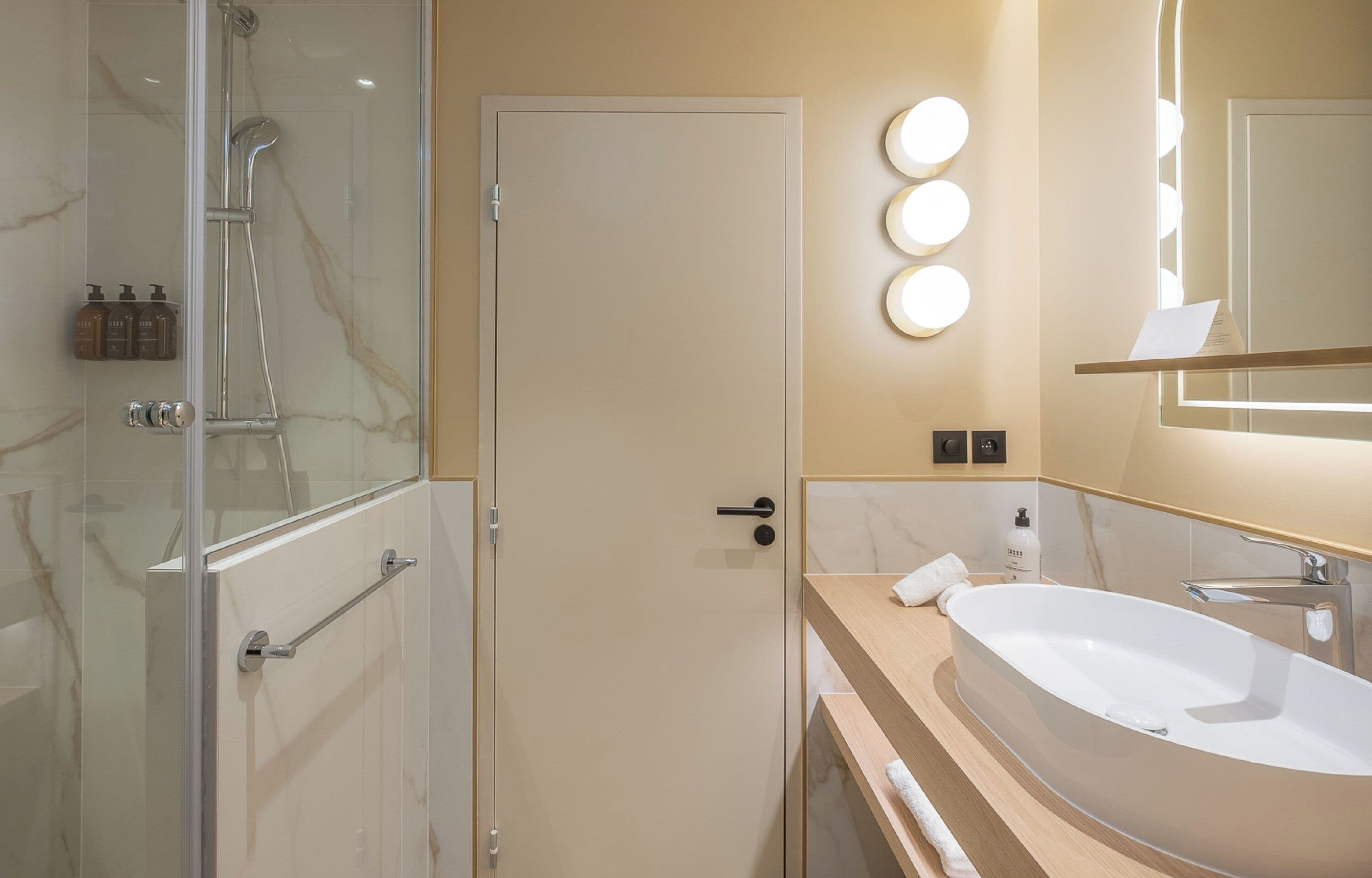 Un baño moderno con cabina de ducha de vidrio, un lavabo ovalado grande y un mueble de tocador con espejo.