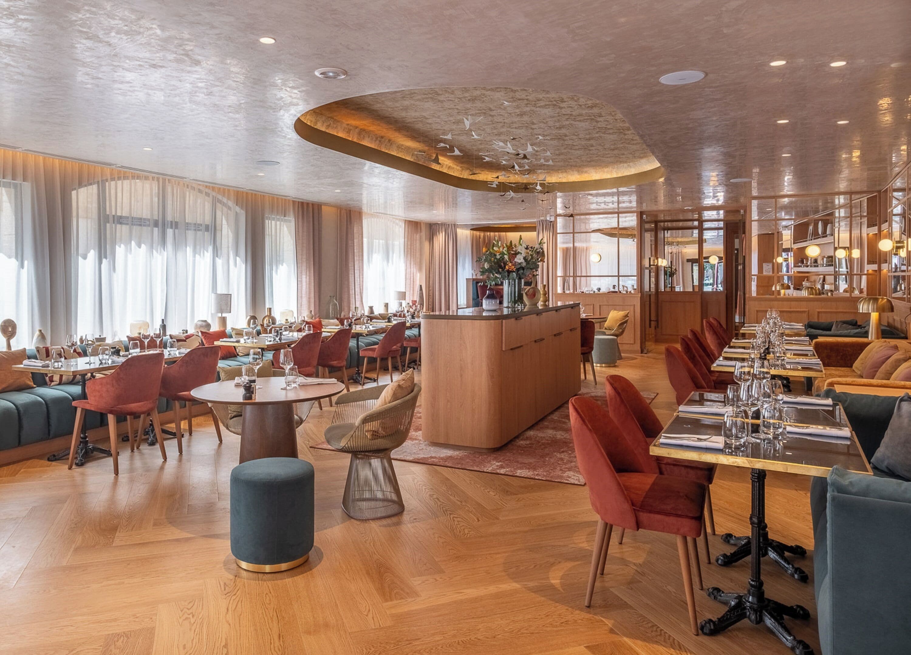 Un restaurante moderno con suelo de madera, asientos rojos y azules, y una isla central.