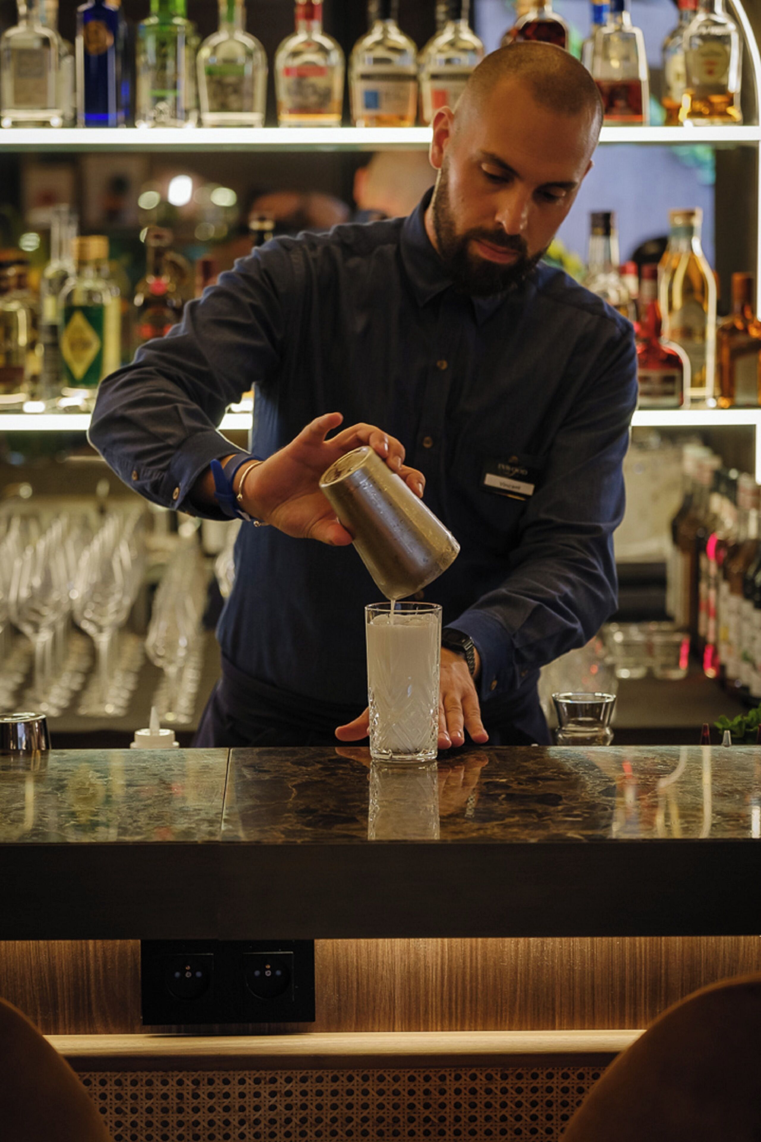 A bartender pouring a drink into a glass.