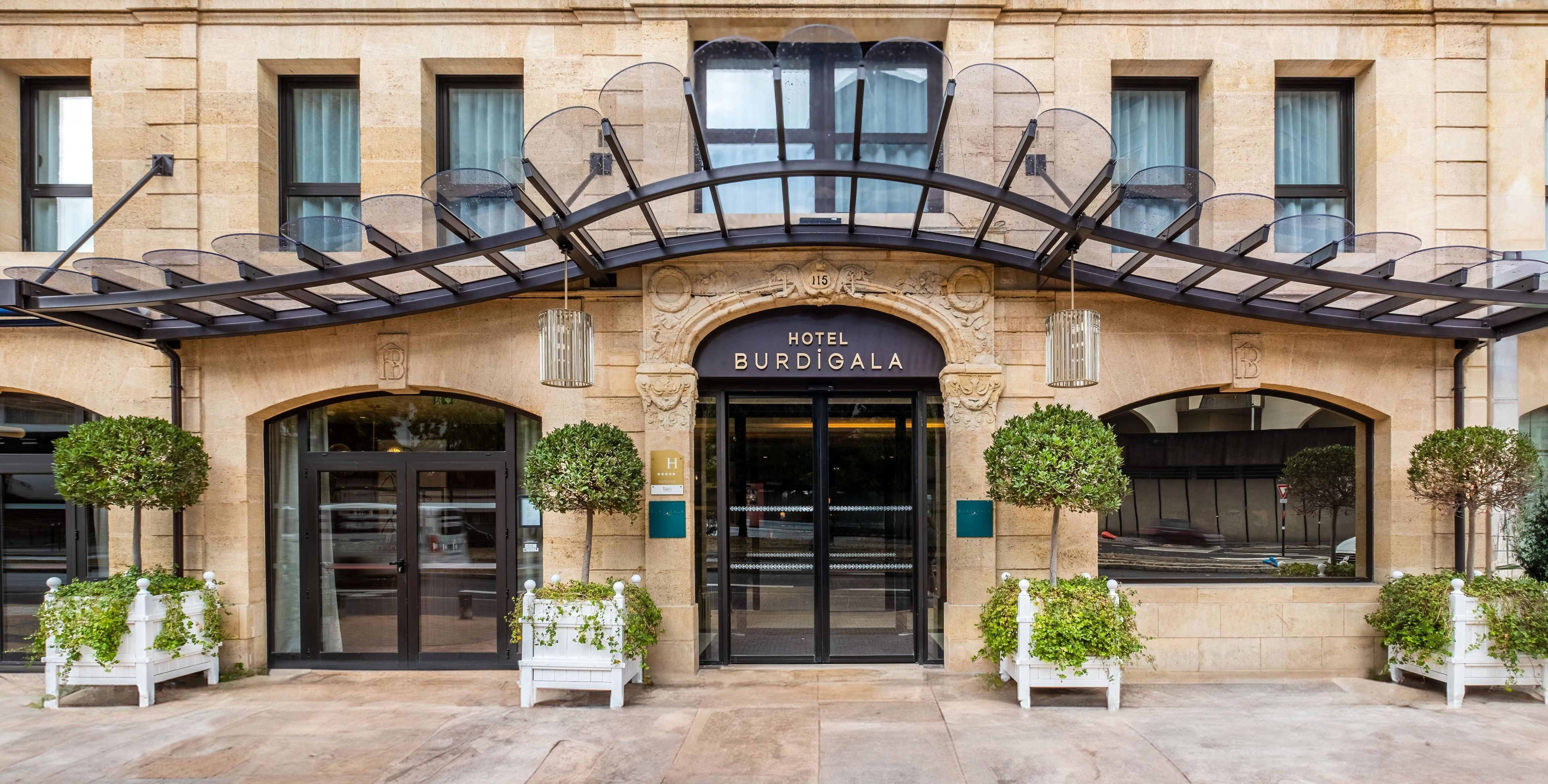 Entrada de un hotel con fachada clásica, puerta de cristal y un letrero que dice 'HOTEL BURDI GALA'.