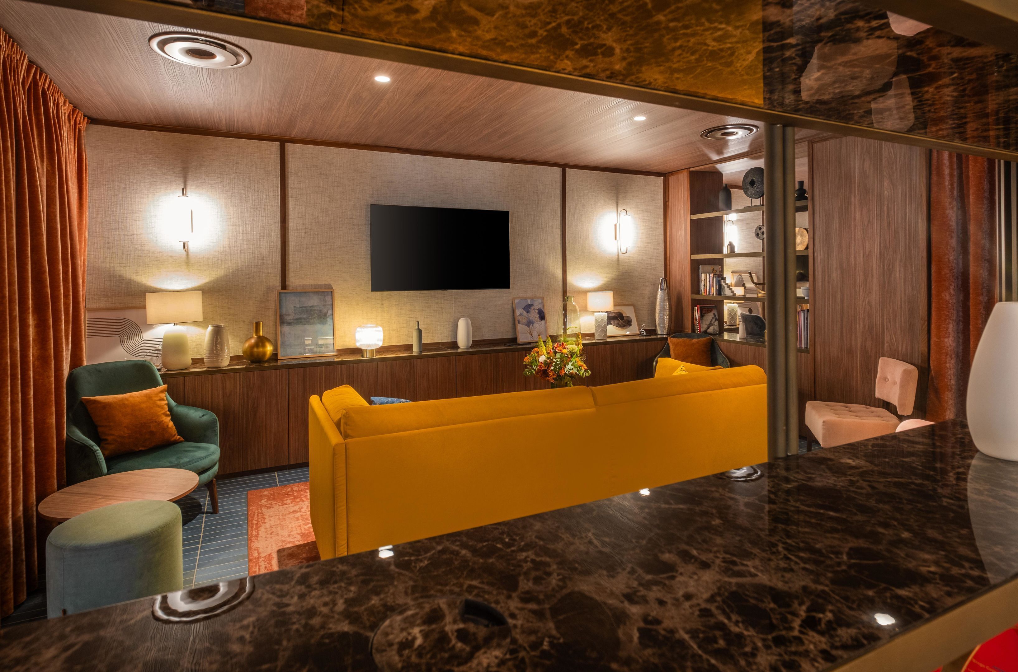 Een modern interieur met een bank, stoelen, een flatscreen-tv en een marmeren aanrecht.