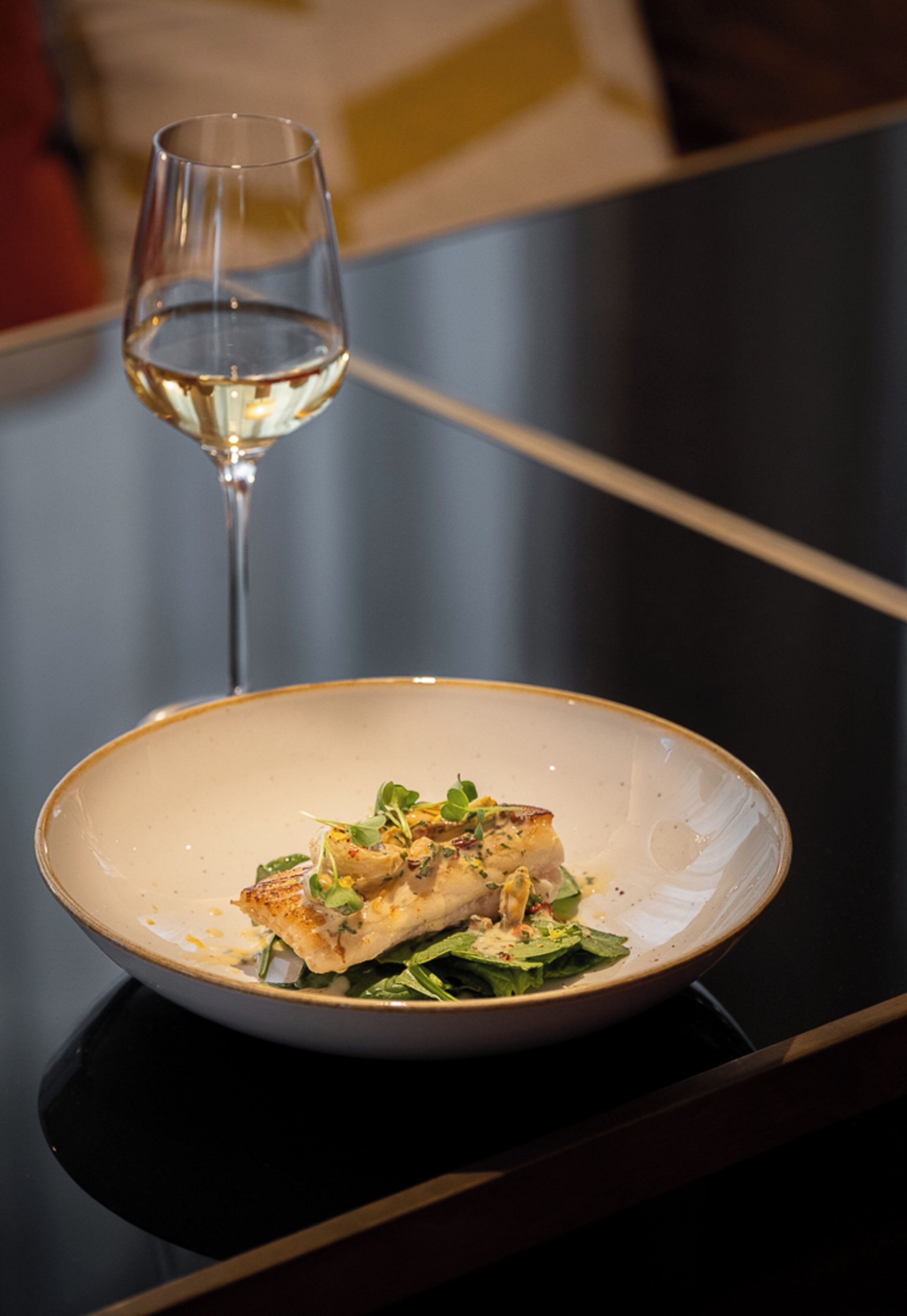 A dining table with a plate of food and a wine glass.