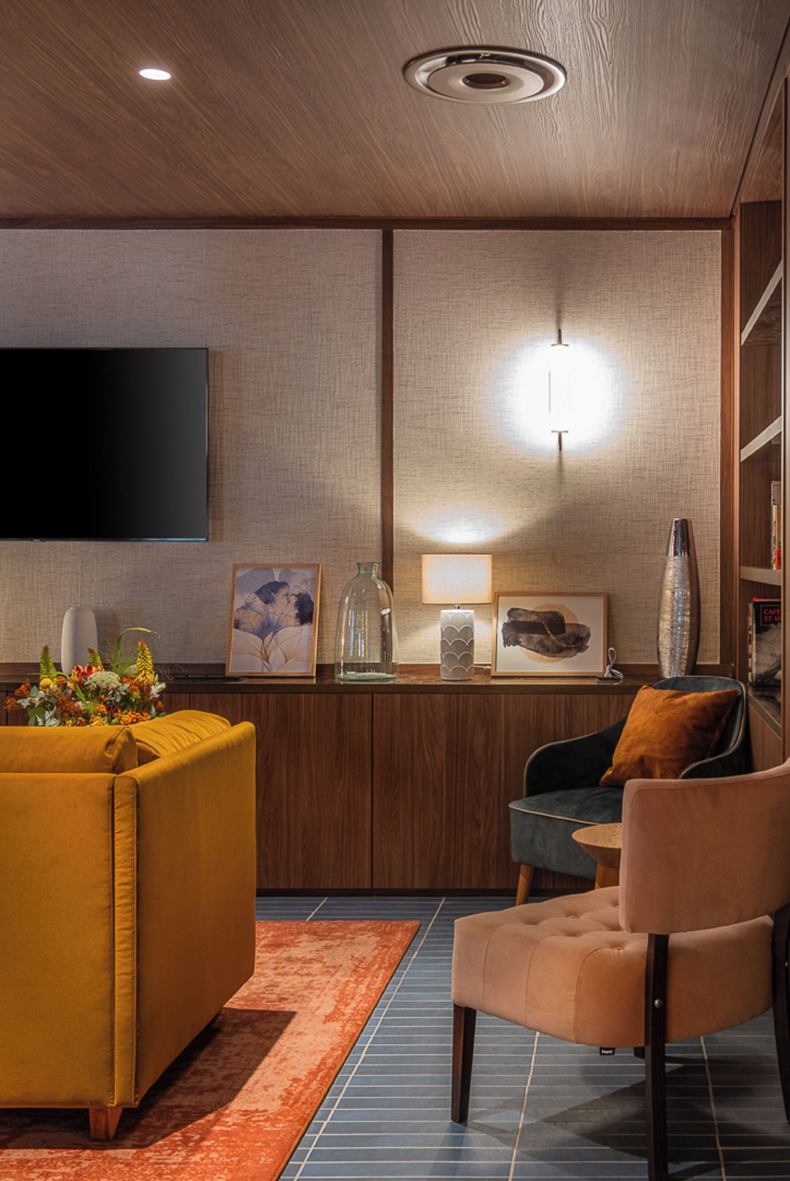 Una sala de estar moderna con un televisor de pantalla plana, un sofá, una silla y una mesa de centro.