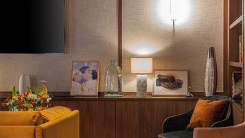 Una sala de estar moderna con un televisor de pantalla plana, un sofá, una silla y una mesa de centro.
