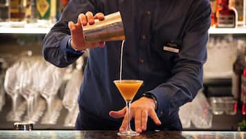 Un barman sirviendo una bebida en una copa de martini.
