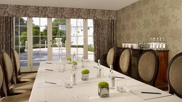 A conference room with a long table, chairs, and a view through large windows.