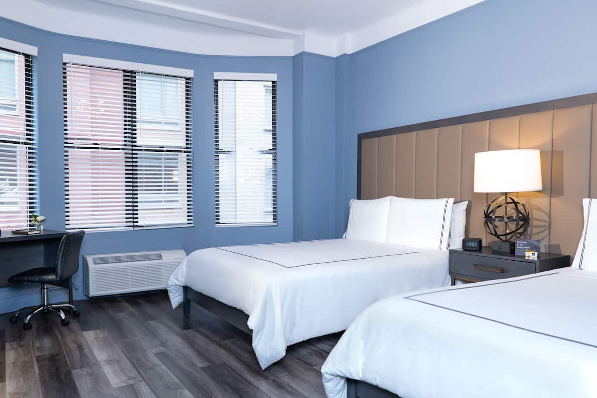 Habitación de hotel con dos camas, un escritorio y una silla.