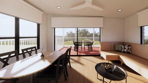 A modern interior with a dining area, a seating area with a sofa, and large windows offering a view. - Discovery Parks - Rockhampton (Norman Gardens)