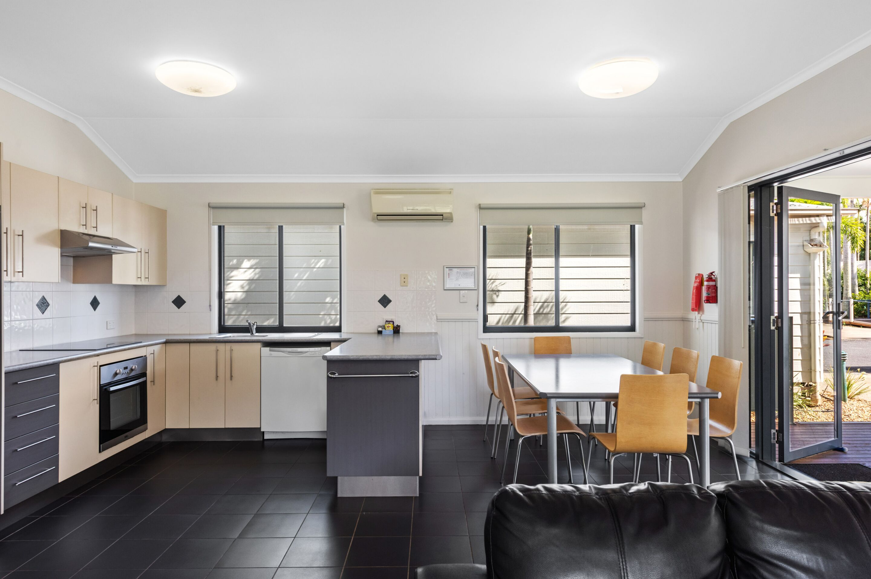 Una cocina moderna con comedor, que incluye una isla central, horno integrado y una mesa con sillas.