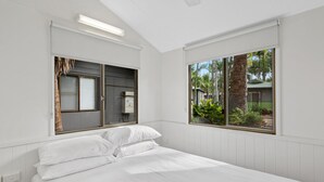 A bedroom with a bed, white walls, and large windows. - Discovery Parks - Rockhampton (Norman Gardens)