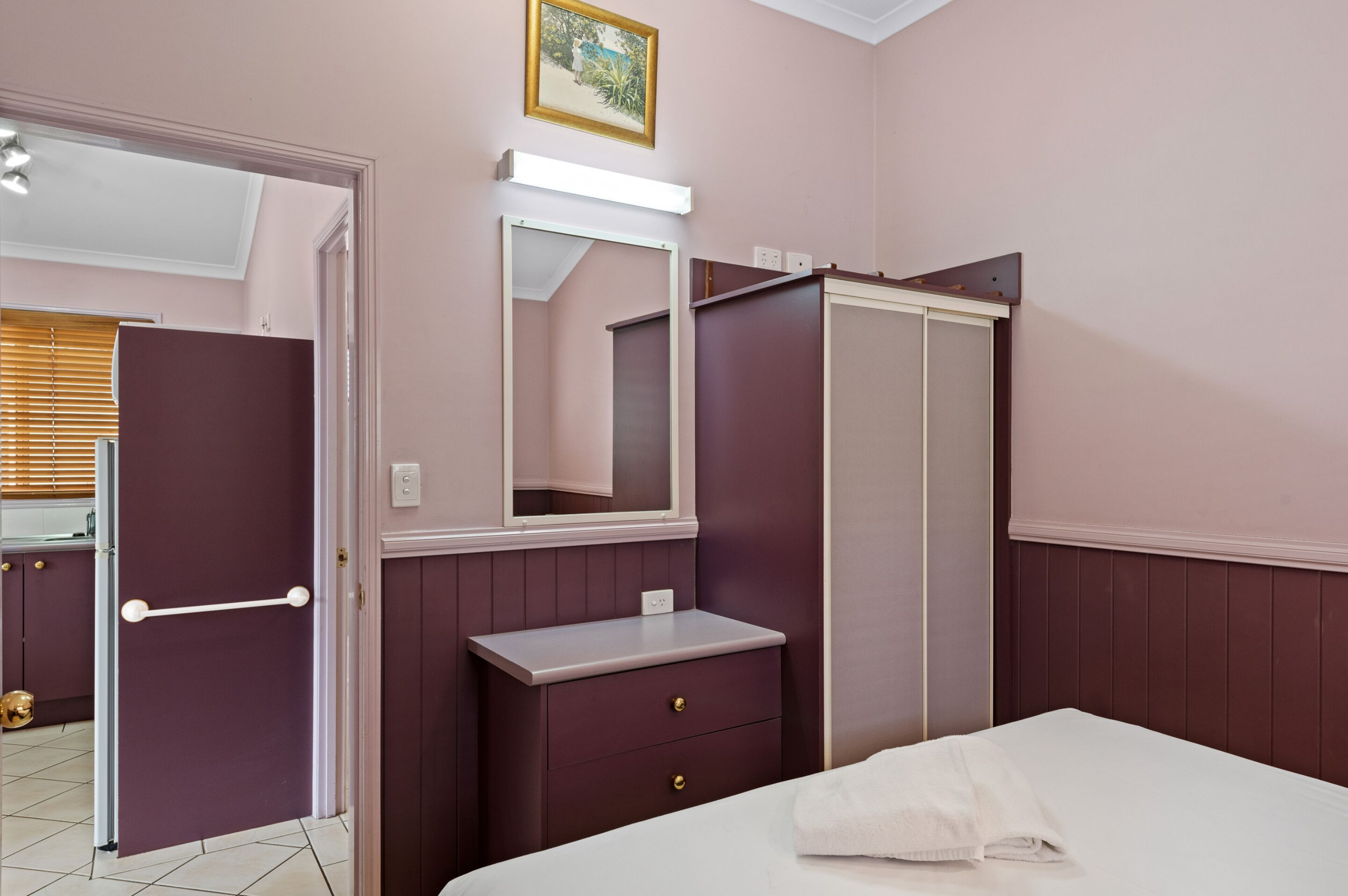 A bedroom with a bed, a dresser, a mirror, and a door.