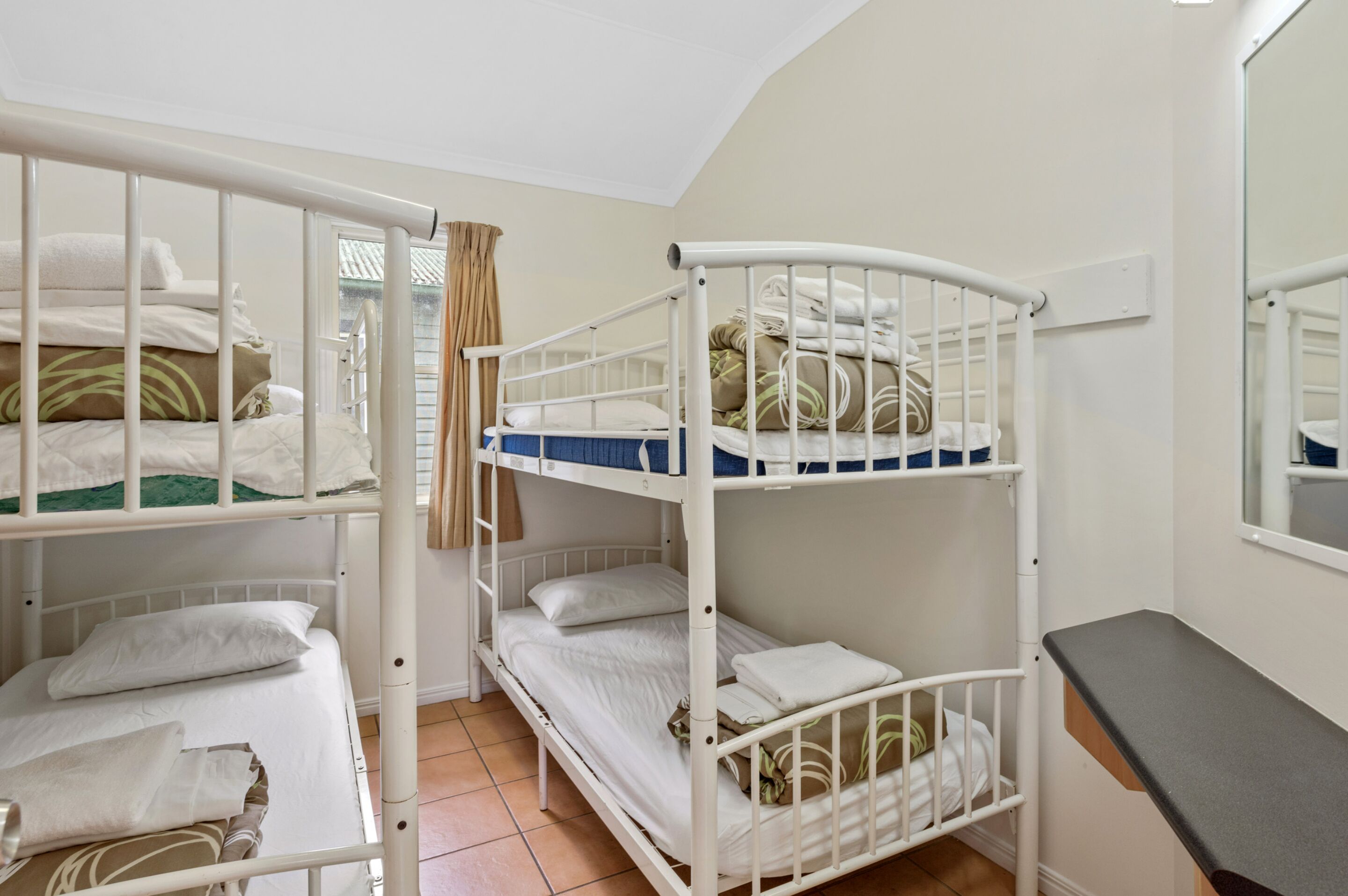 A bunk bed room with white railings, a mirror, and a small table.