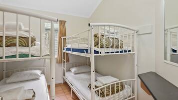 A bunk bed room with white railings, a mirror, and a small table.