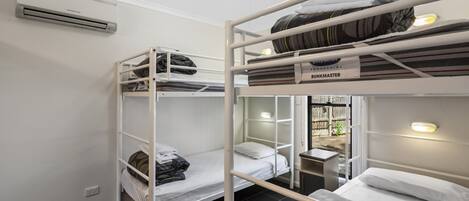 Un dormitorio tipo camarote con tres literas, una mesita pequeña y una ventana con vistas al exterior.