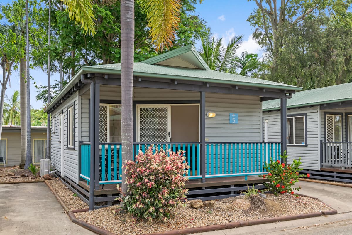 A single-story, two-room mobile home with a porch and a small garden.
