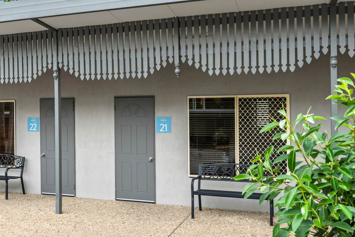 A building with two doors labeled 21 and 22, a bench, and a plant in the foreground.