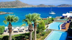 A resort with a swimming pool, beach area with umbrellas, and a view of the sea and mountains. - Elounda Bay Palace, a Member of the Leading Hotels of the World (Agios Nikolaos)