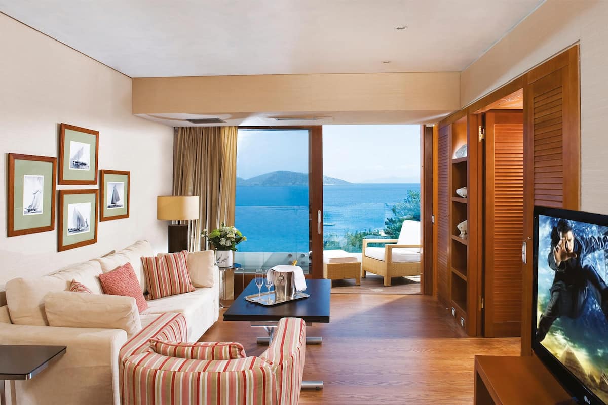 Amplia sala de estar con un gran ventanal que ofrece vistas al mar y a la montaña. Hay un sofá, una mesa de centro y un televisor.