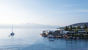 A marina with boats, a sailboat, and modern buildings along the waterfront. - Elounda Bay Palace, a Member of the Leading Hotels of the World (Agios Nikolaos)