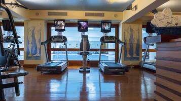 Un gimnasio con cintas de correr, bicicletas estáticas y una máquina de remo.
