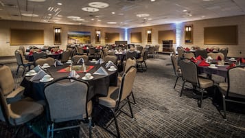 A conference room with round tables, chairs, and a podium.