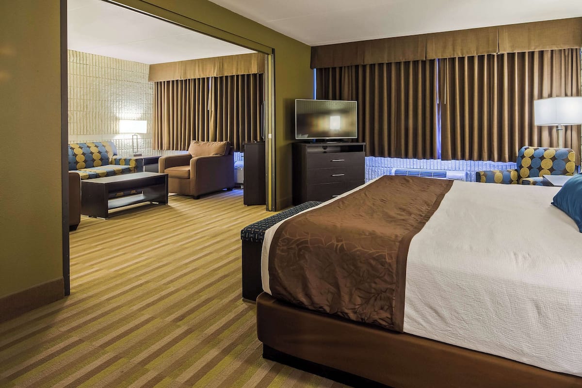 A hotel room with a large bed, a sofa, a desk, a television, and a wardrobe.