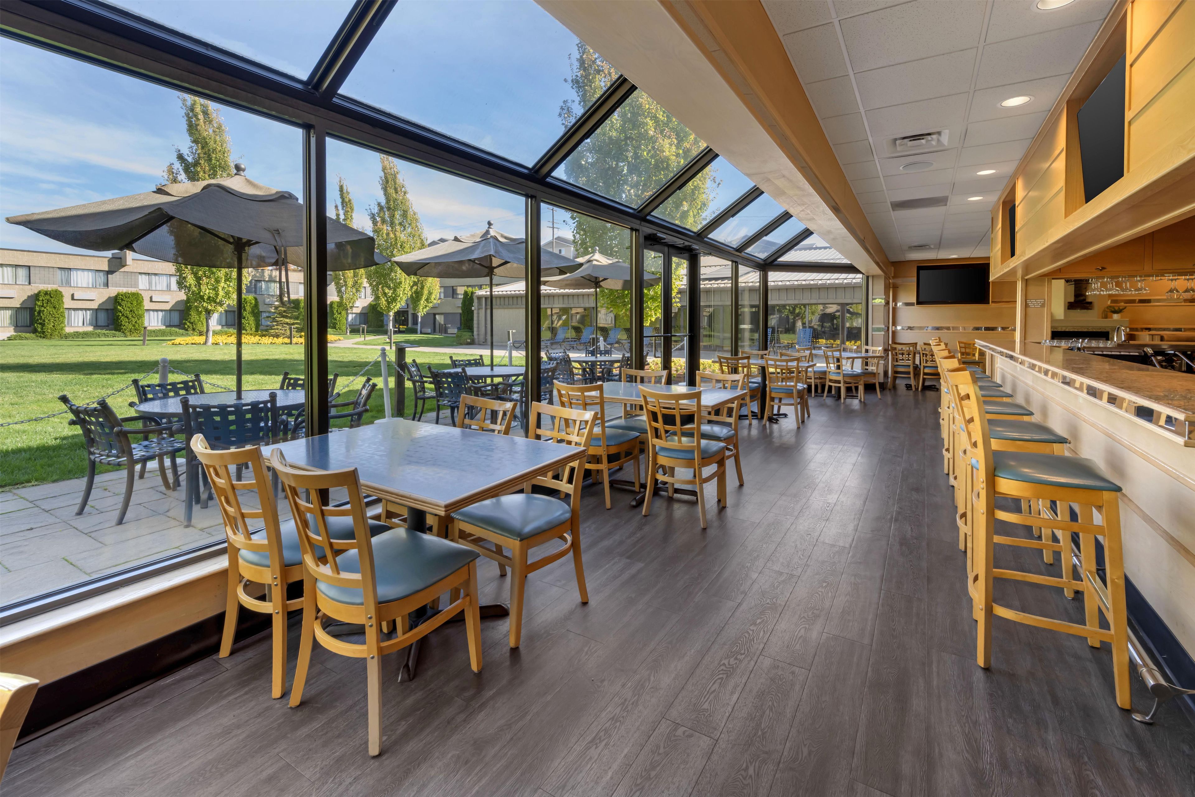 A restaurant with outdoor seating, large windows, and a view of the surrounding area.