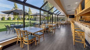 A restaurant with outdoor seating, large windows, and a view of the surrounding area.