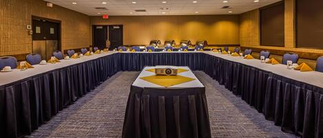 A conference room with a long table, multiple chairs, and a projector.