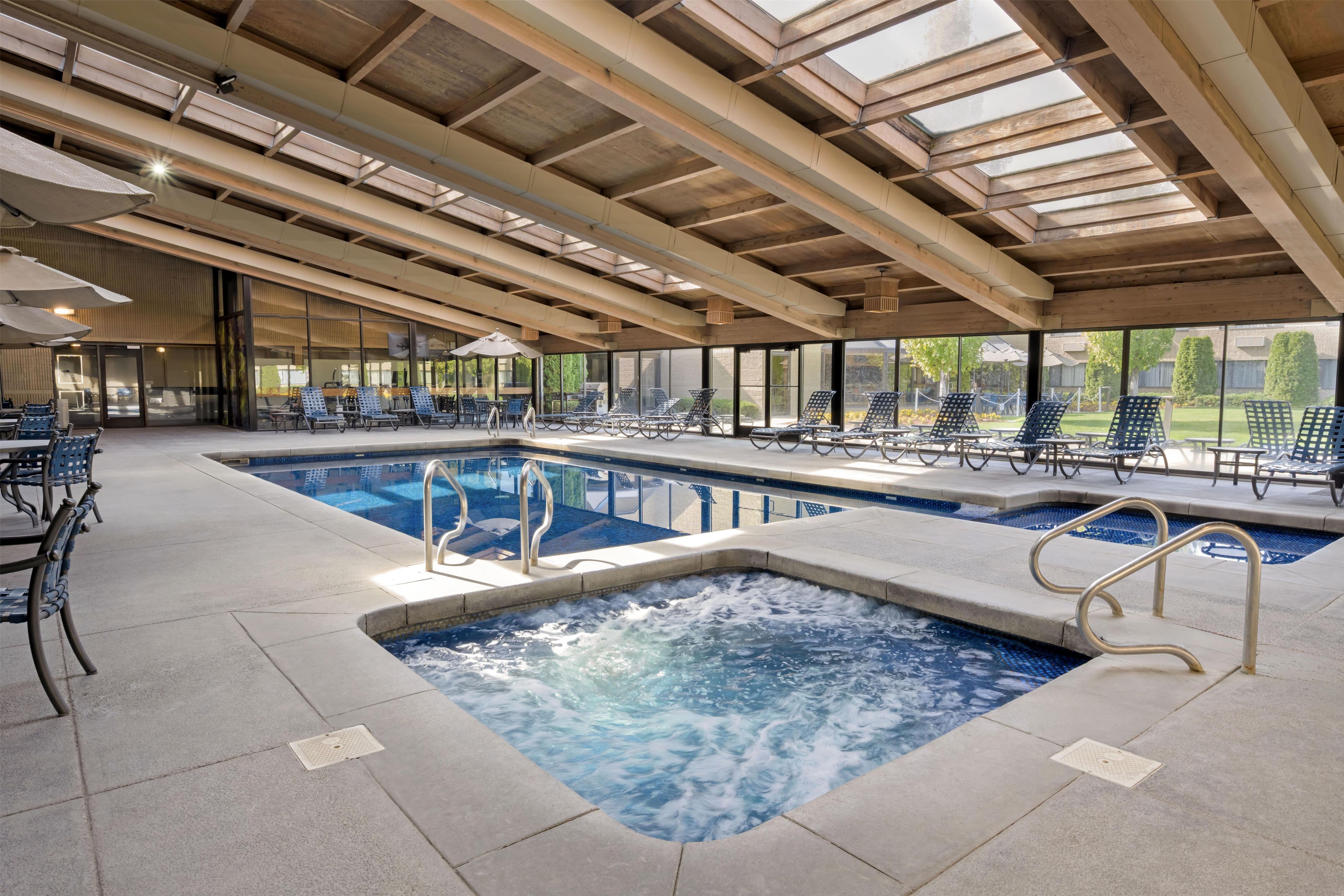 An indoor swimming pool with lounge chairs and a covered seating area.