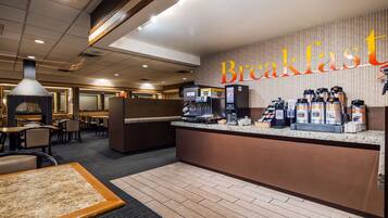 A breakfast area with a counter, coffee machines, and seating.