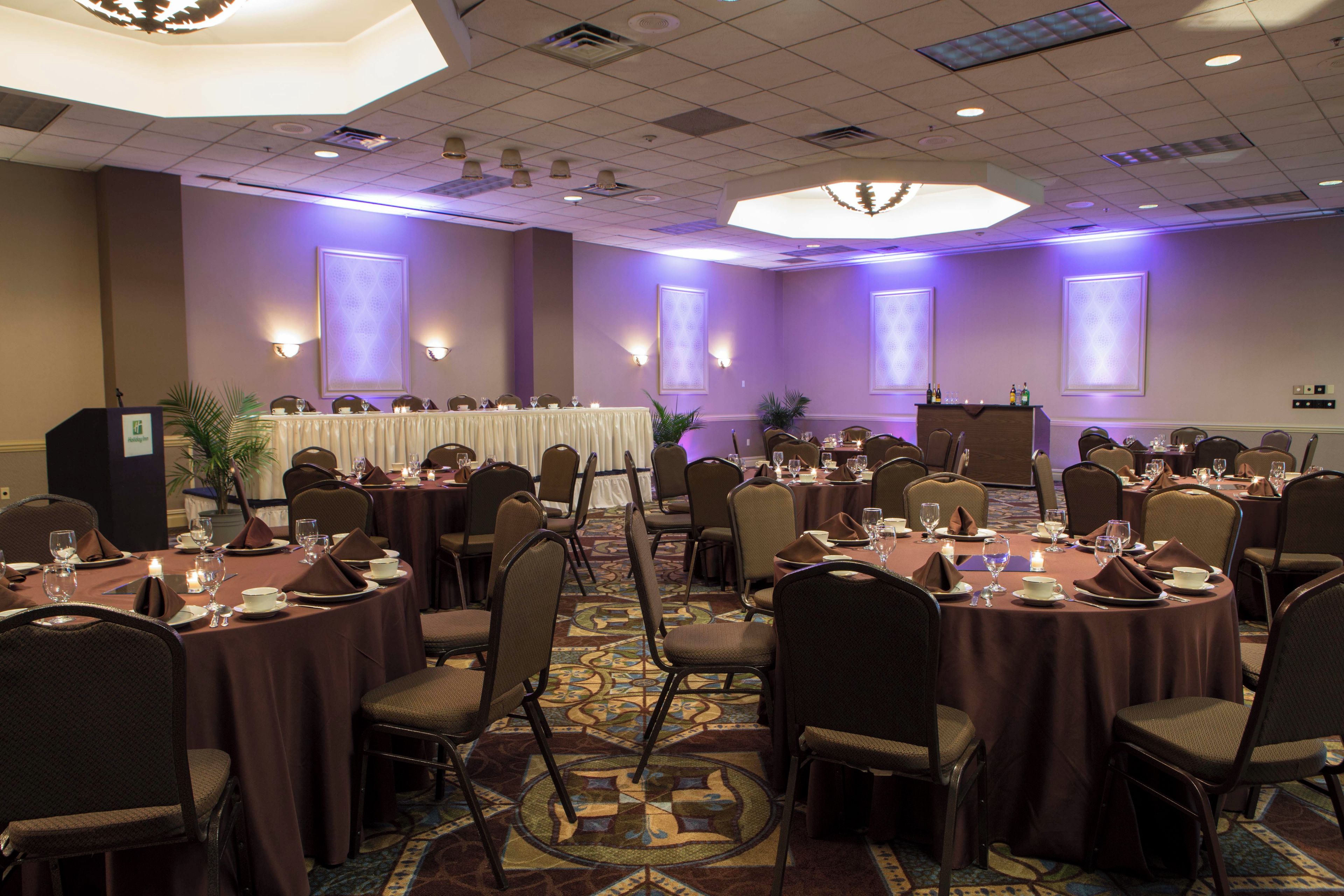 A conference room with round tables, chairs, and a podium.