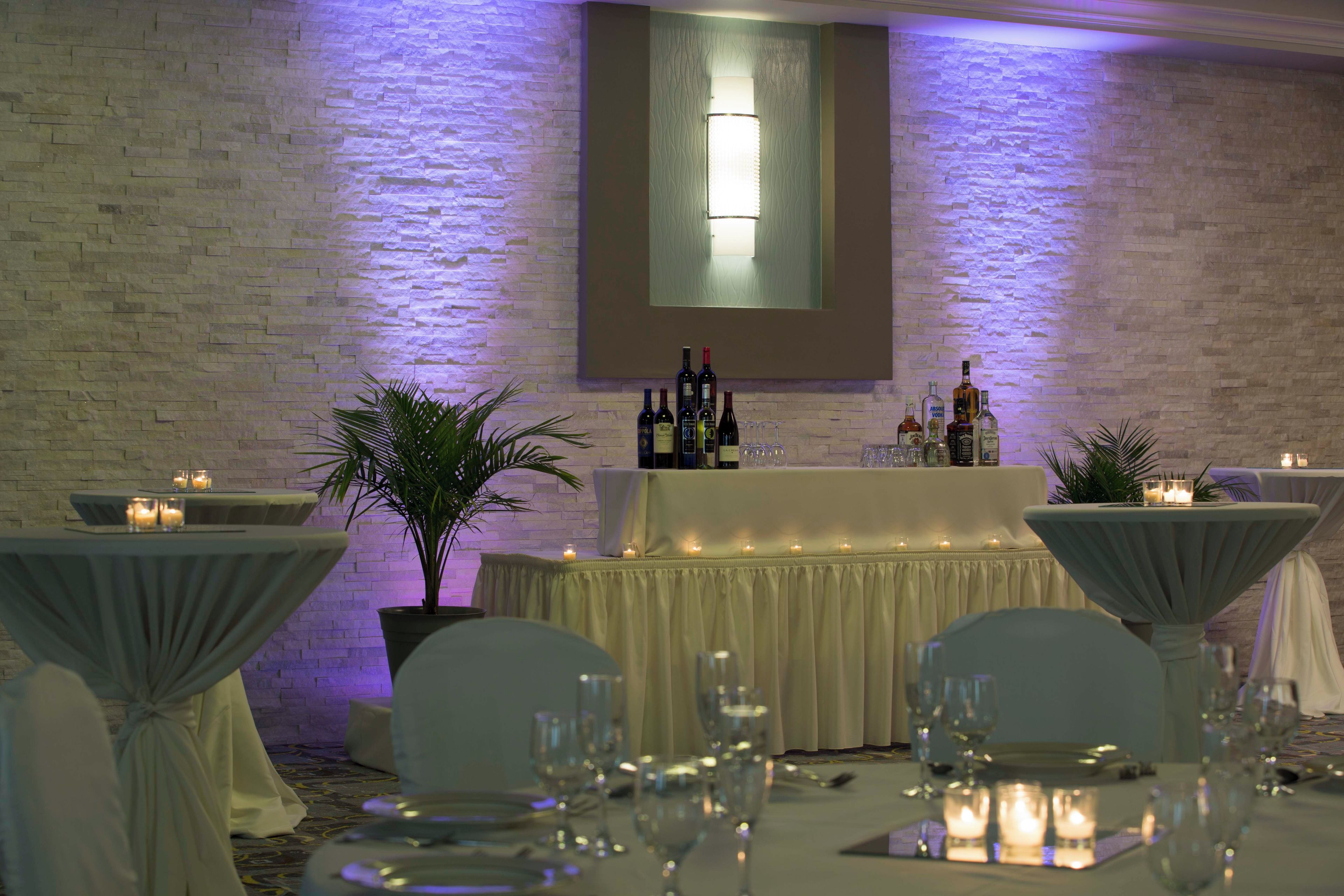 A banquet hall with tables set for a formal event, featuring a brick wall backdrop and ambient lighting.