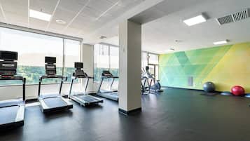 Un gimnasio con cintas de correr, bicicletas estáticas y pelotas de ejercicio.