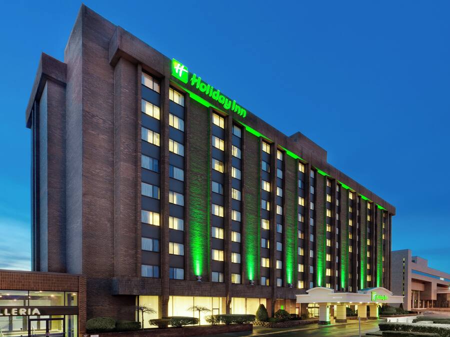 En flervåningsbyggnad med en framträdande grön skylt som visar att det är ett Holiday Inn-hotell.