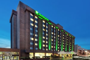 A multi-story building with a prominent green sign indicating a Holiday Inn.