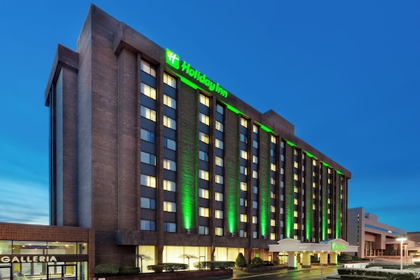 A multi-story building with a prominent green sign indicating a Holiday Inn.