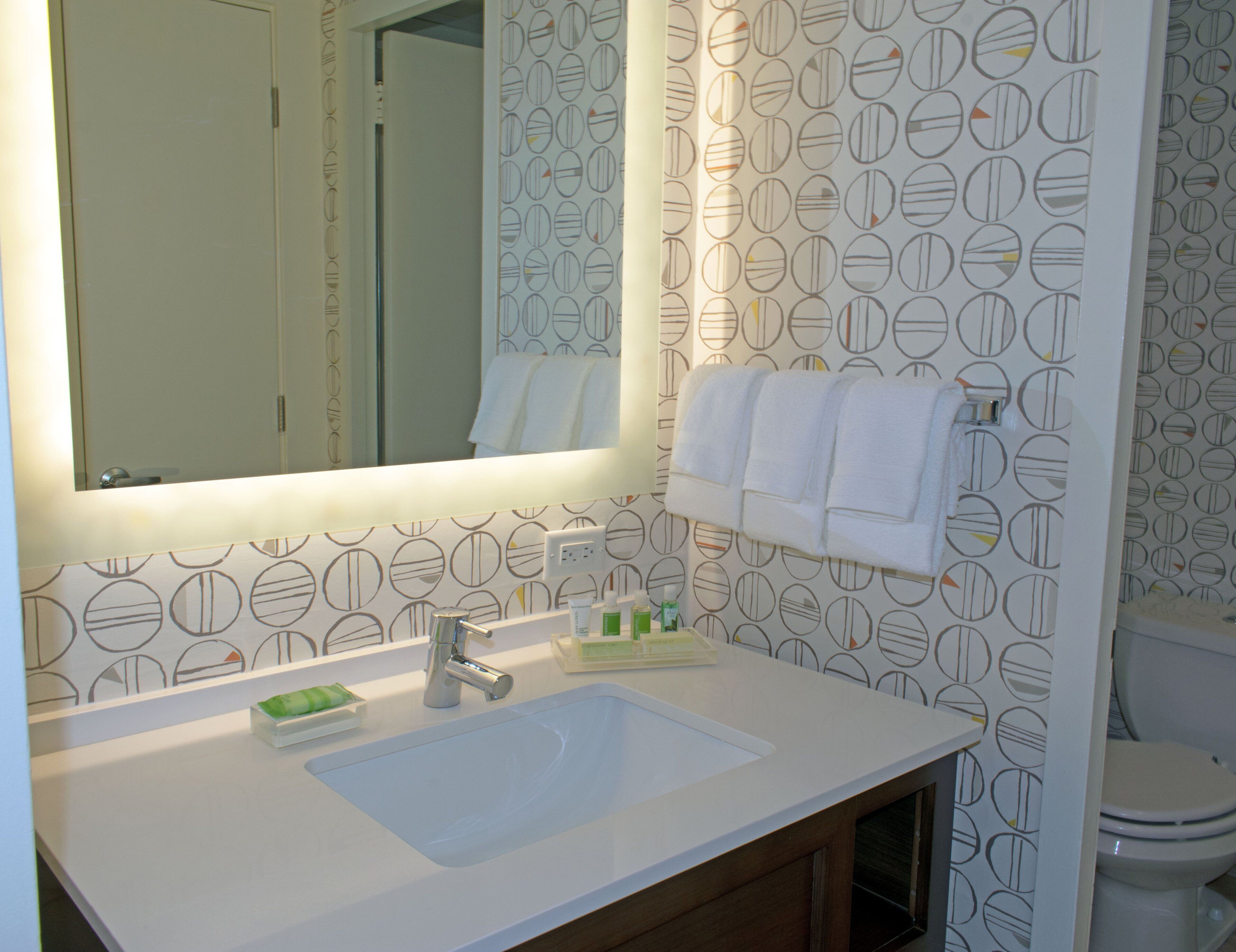 A bathroom with a white sink, mirror, and towel rack.