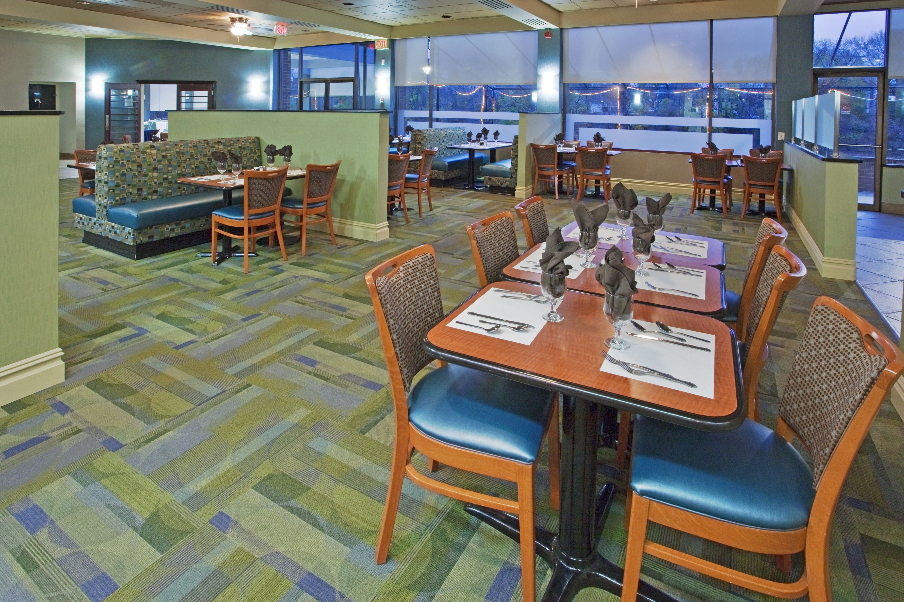 A dining area with tables set for four, chairs, and a patterned carpet.